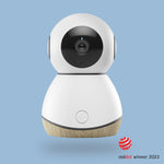 A modern white and wood-colored baby monitor camera with a 360-degree rotatable camera lens, designed for wall mounting or placing opposite at eye level in a nursery.