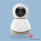 A modern white and wood-colored baby monitor camera with a 360-degree rotatable camera lens, designed for wall mounting or placing opposite at eye level in a nursery.