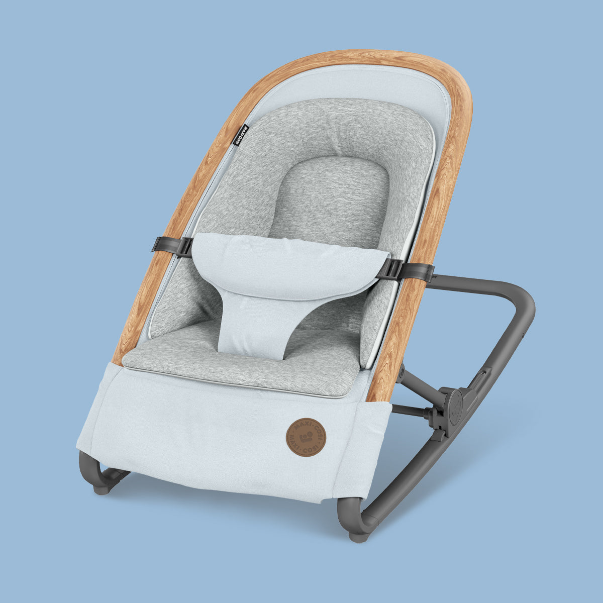 A relaxing Maxi-Cosi Kori Rocker with a wooden seat and a blue background from Maxi-Cosi UAE.